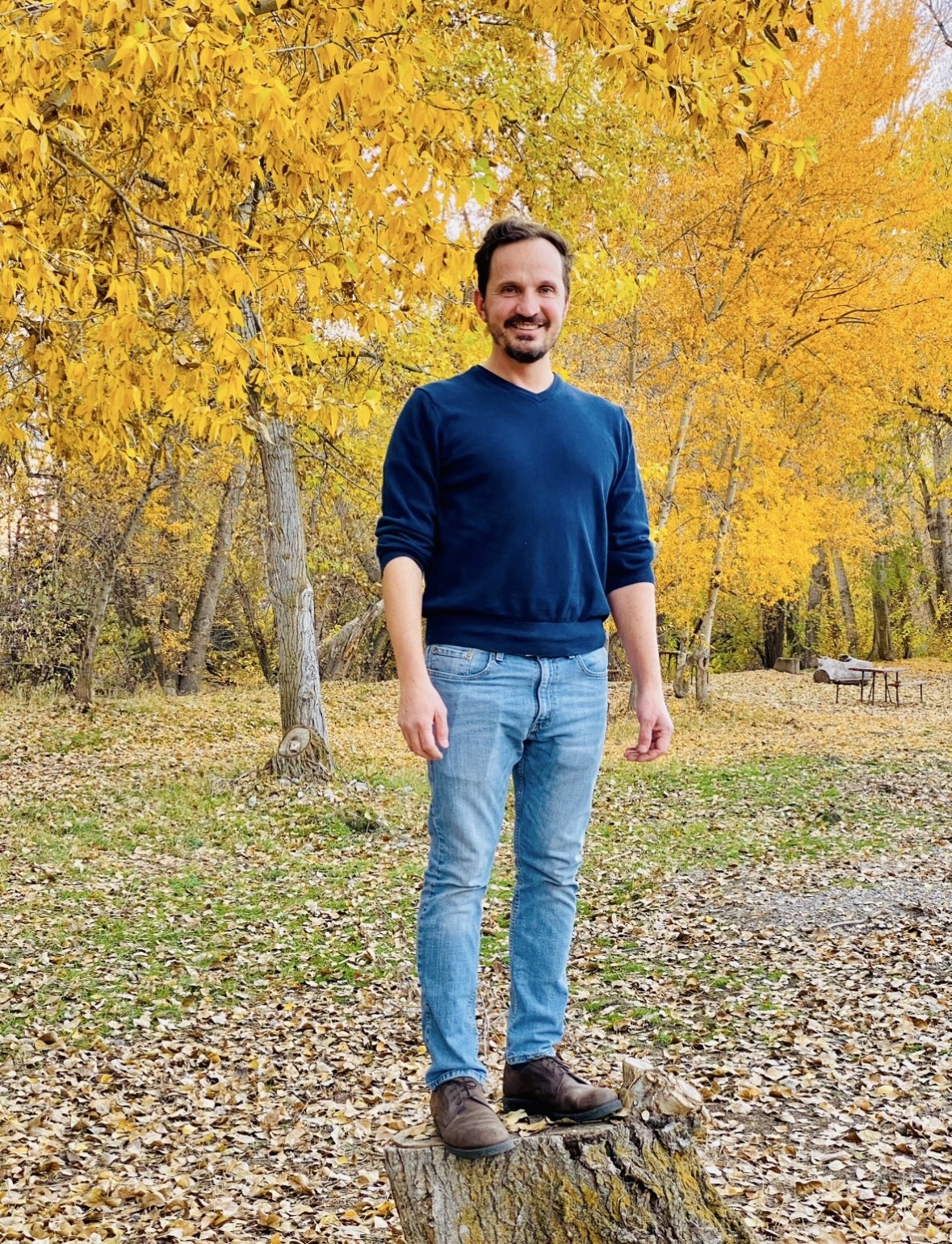 Jared Harding WIlson in front of a roow of trees with beautiful gold fall leaves.