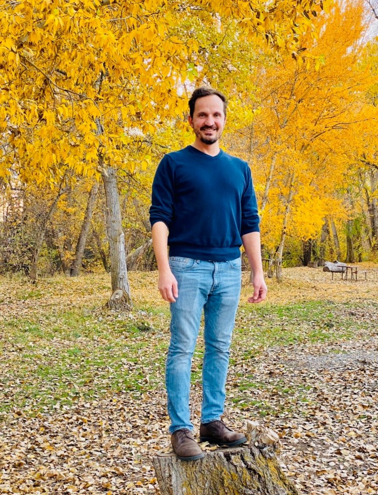 Jared Harding WIlson in front of a roow of trees with beautiful gold fall leaves.