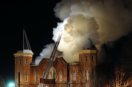 Nighttime photo of the Provo Tabernacle fire with a fire department ladder truck and a huge plume of dark smoke.