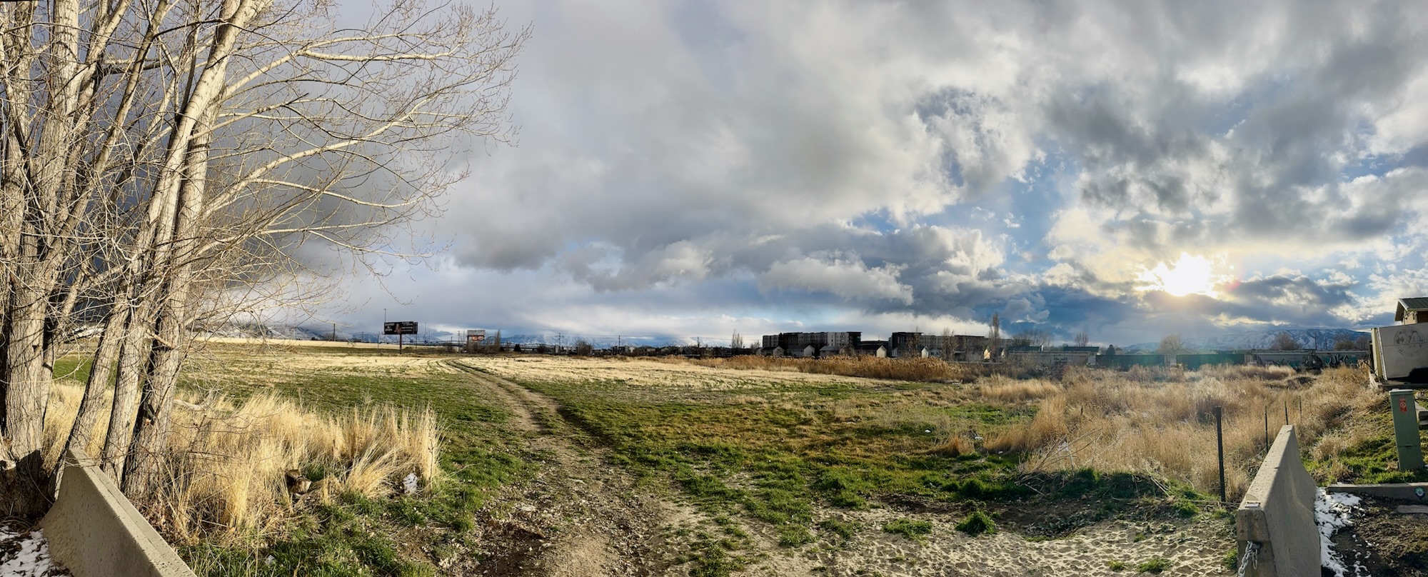 A wide panoramic sunset view of a field and train cars taken by Jared Harding Wilson.