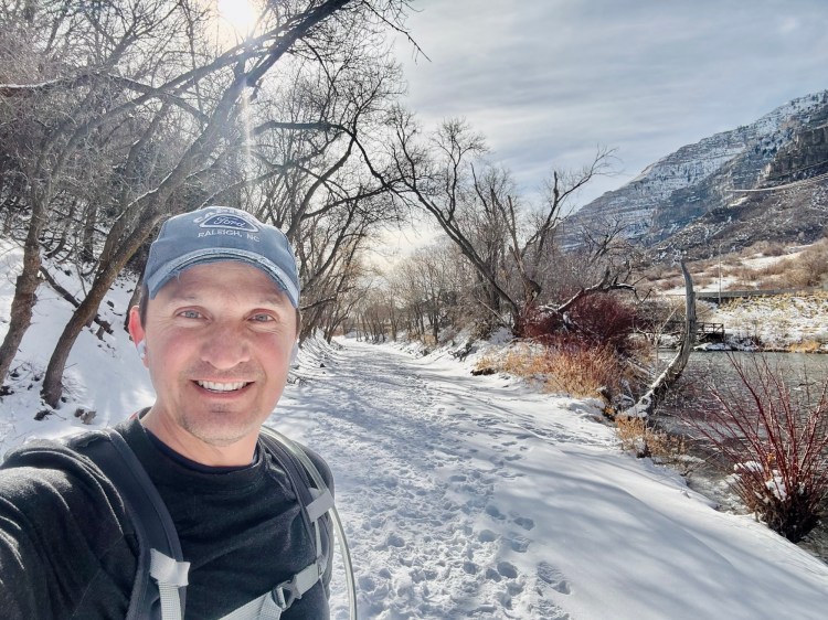 Jared Harding Wilson on a snow-covered trail with the Provo River and a mountain in the background.