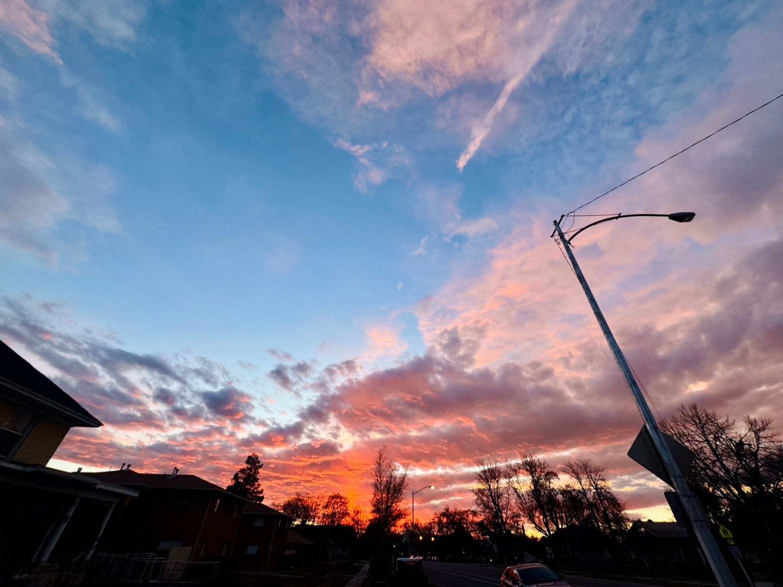 A wide Utah sky showing blue fading into pink and orange clouds above a treeline, photographed by Jared Harding Wilson.