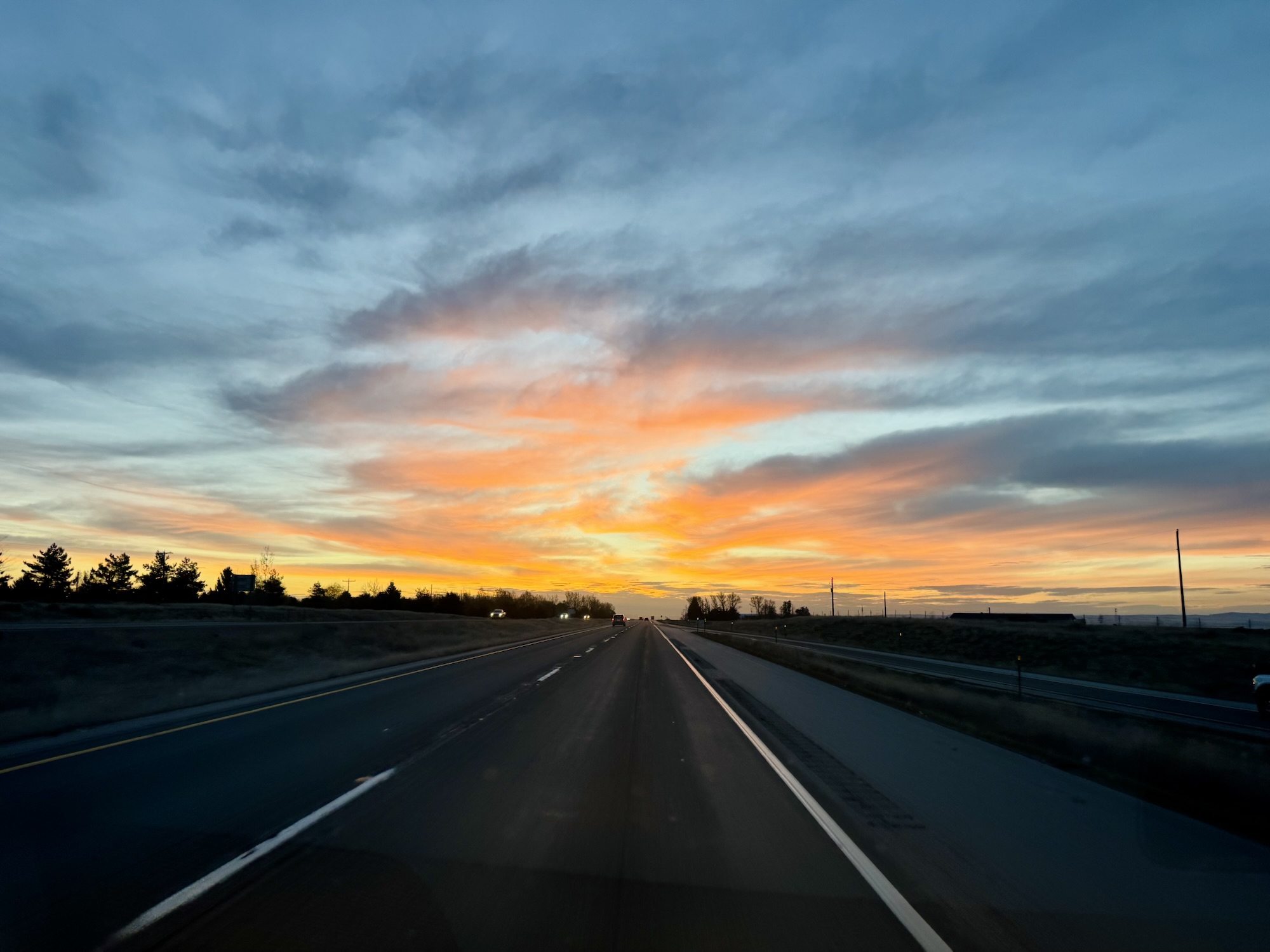 A fiery red and orange sunrise over an open highway during a road trip to Utah, photographed by Jared Harding Wilson.