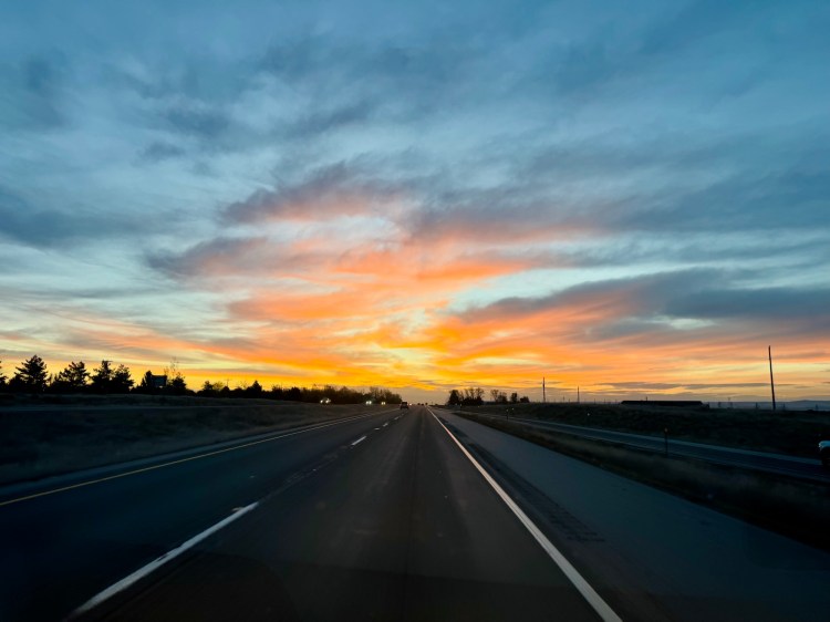 A fiery red and orange sunrise over an open highway during a road trip to Utah, photographed by Jared Harding Wilson.