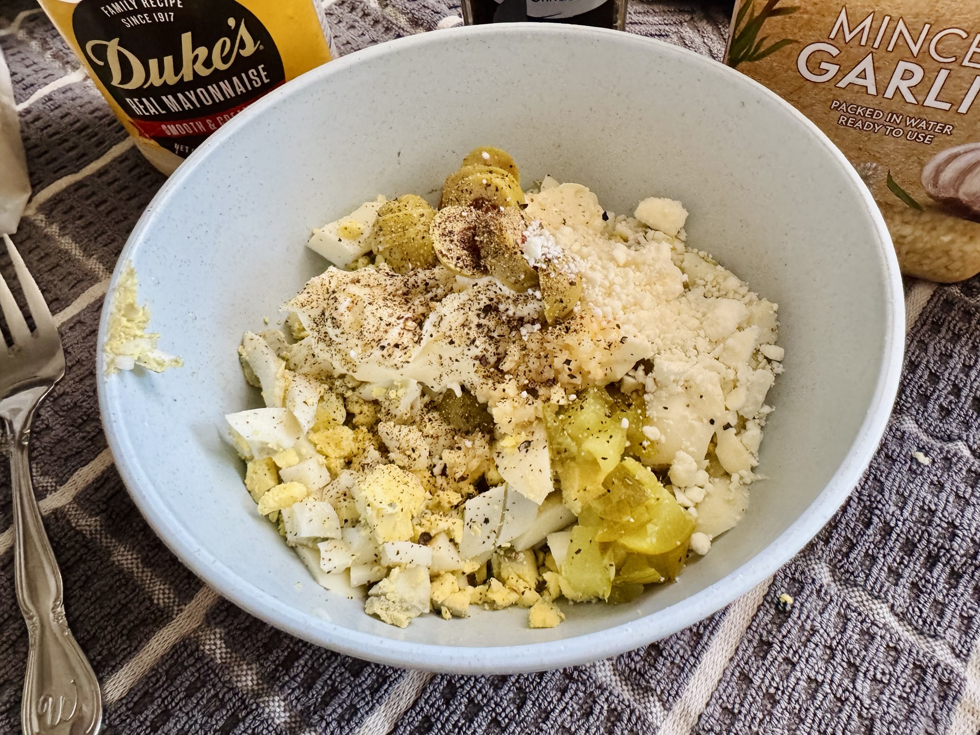 Extreme close-up of unmixed Mediterranean egg salad ingredients—distinct chopped eggs, creamy mayo, sliced green olives, and crumbled feta by Jared Harding Wilson
