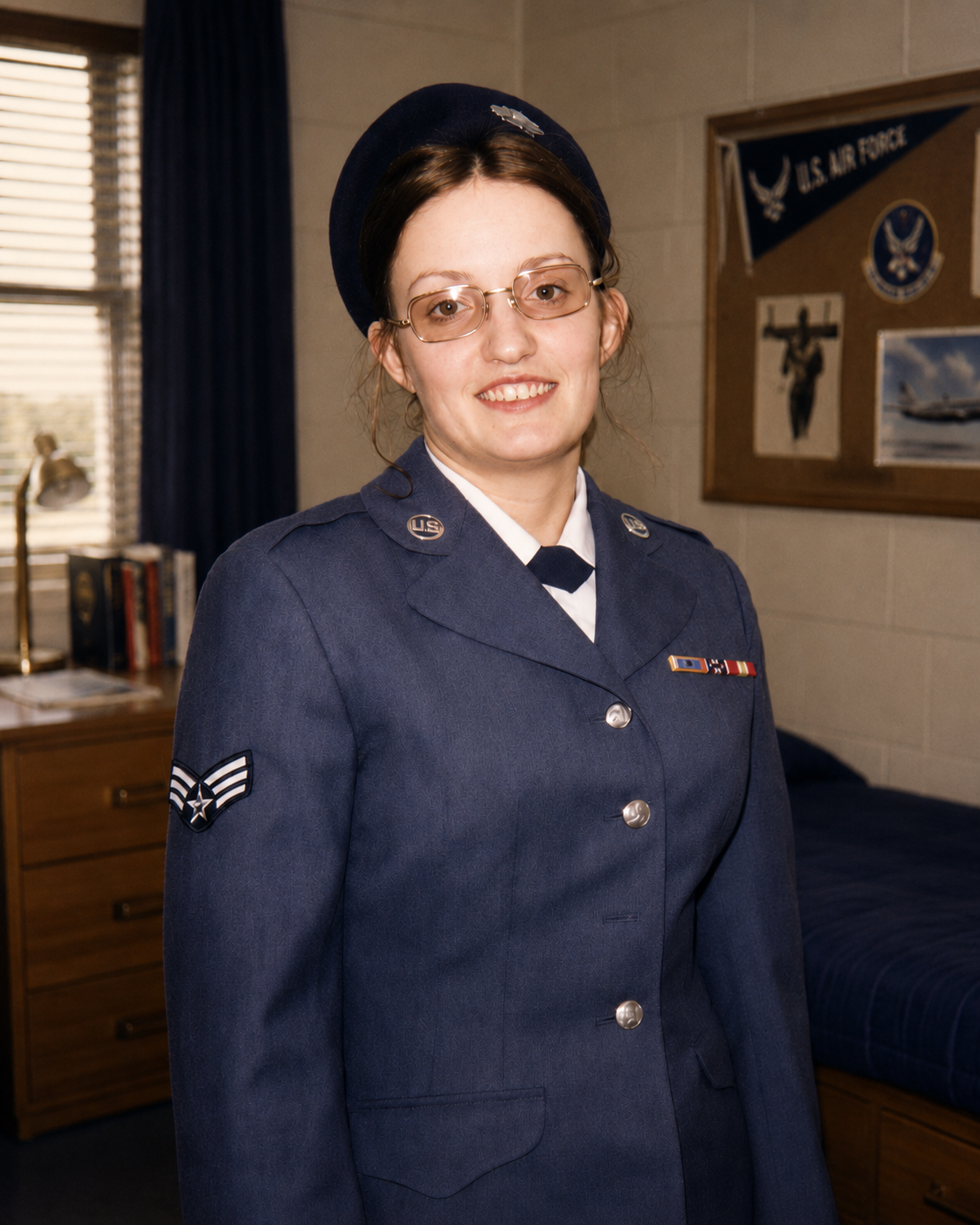 A young female Air Force service member in uniform posing inside her neat, organized military dorm barracks room. Photograph from the collection of Jared Harding Wilson.