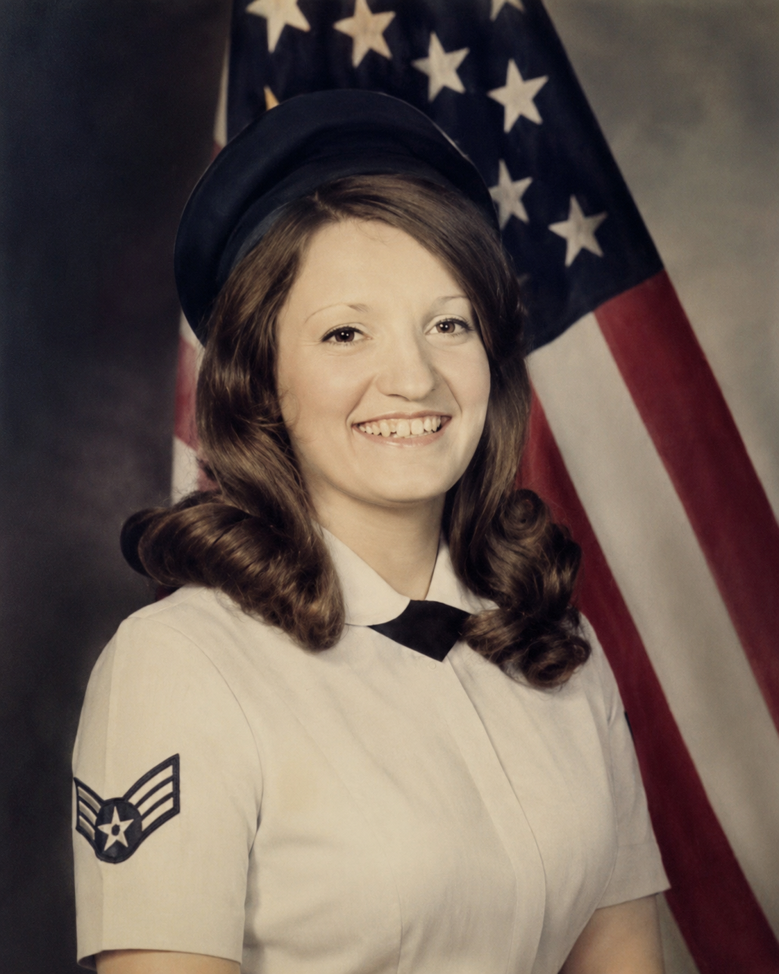 A portrait of a female United States Air Force veteran in full uniform posing in front of an American flag. Photograph from the collection of Jared Harding Wilson.