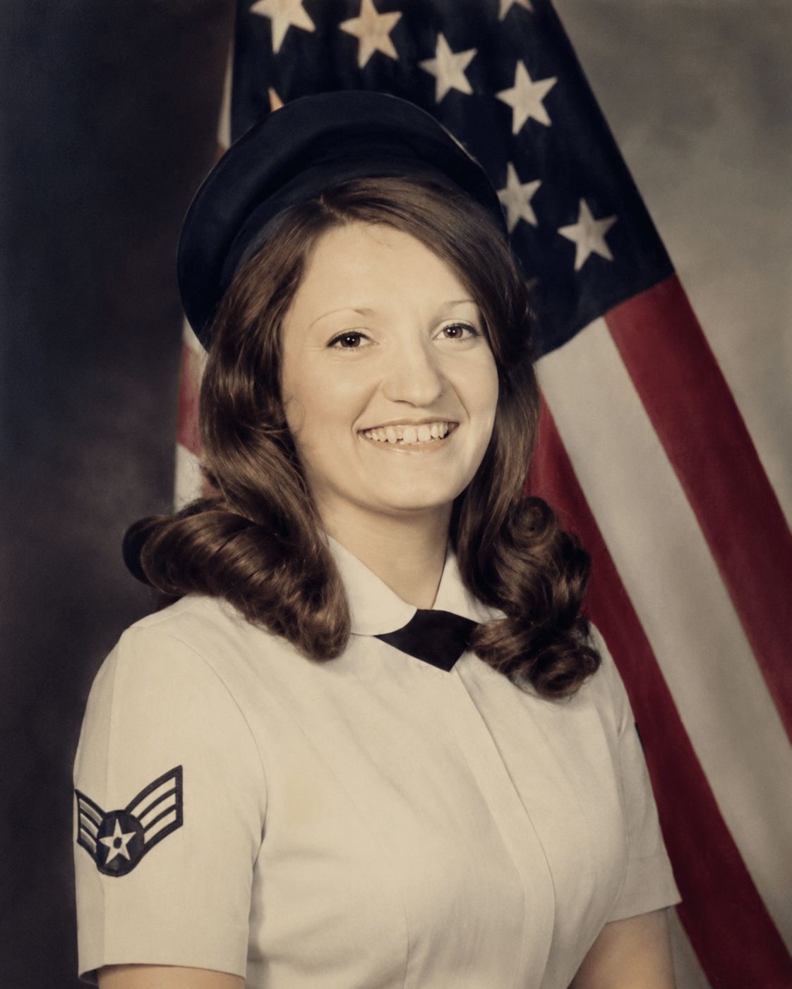 A portrait of a female United States Air Force veteran in full uniform posing in front of an American flag. Photograph from the collection of Jared Harding Wilson.