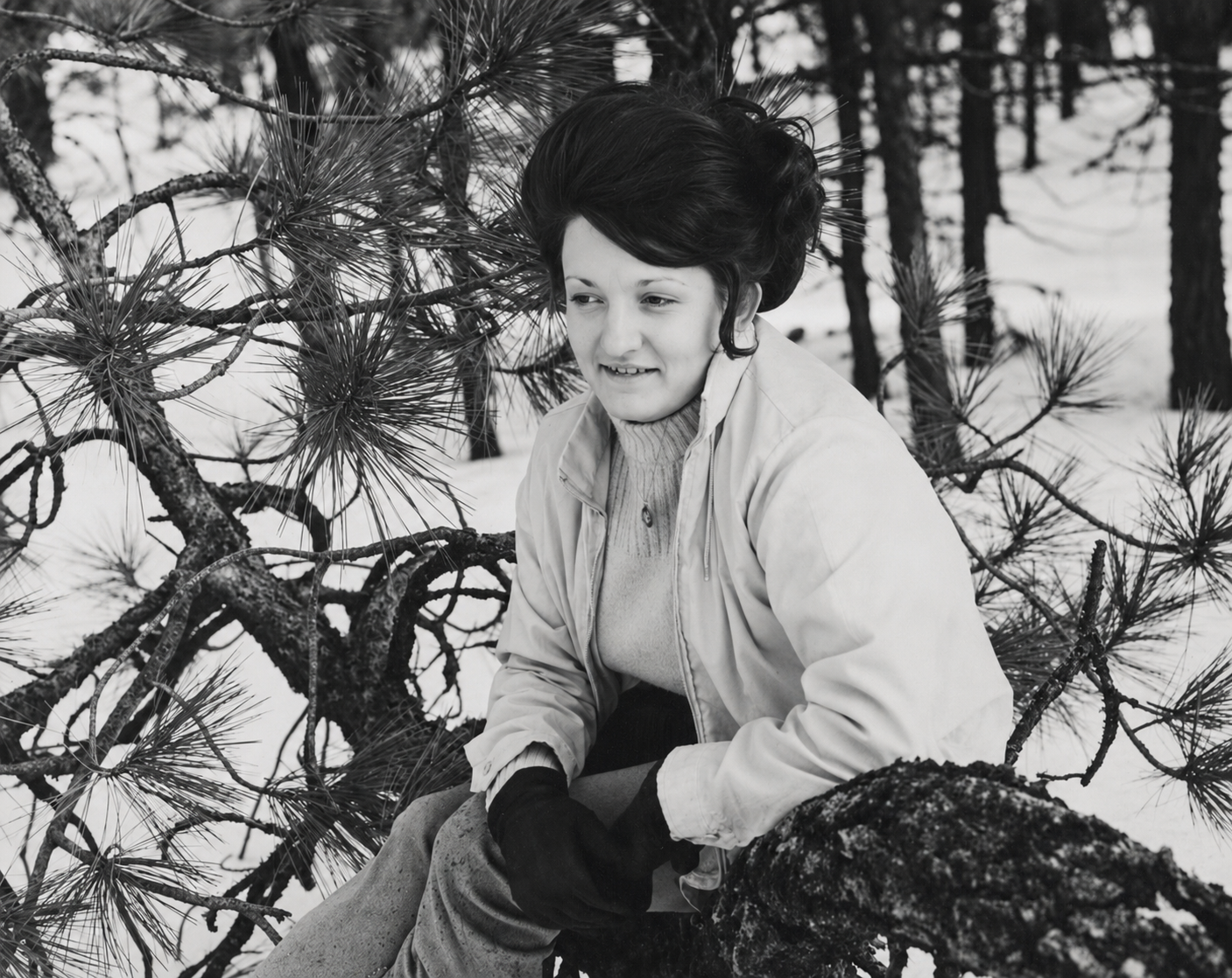 A young woman smiling in casual winter clothing outside in deep snow during her station at a Washington air force base. Photograph from the collection of Jared Harding Wilson.