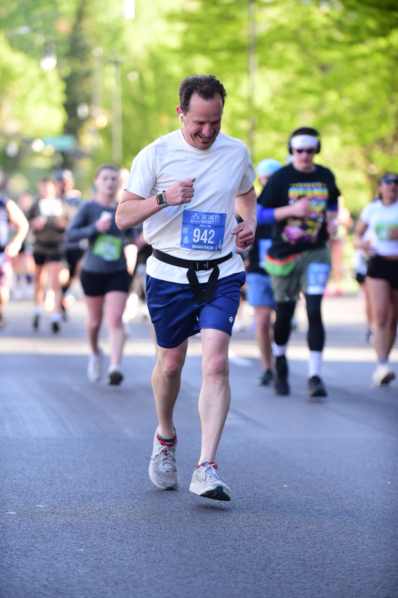 Jared Harding Wilson looking focused and sweaty while running the marathon with a row of green trees in the background.