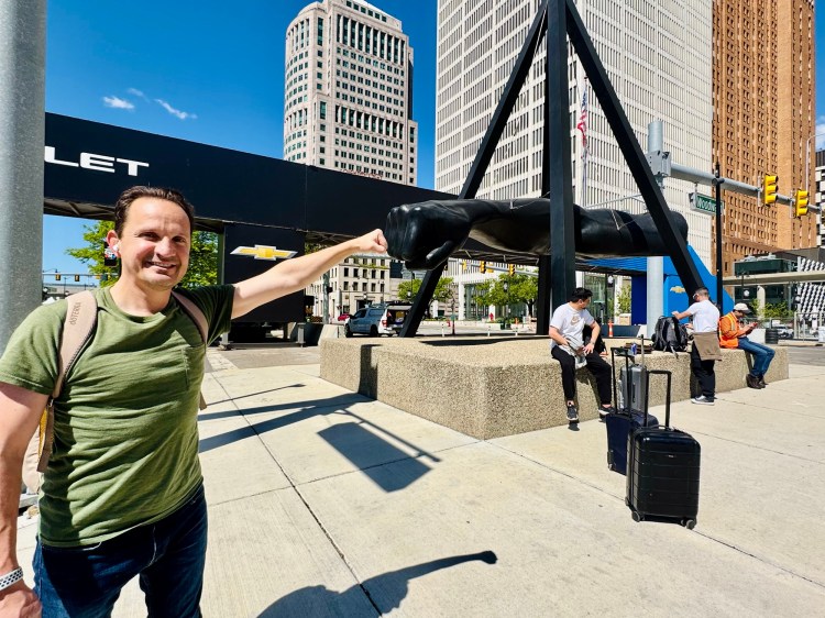 Travel blogger Jared Harding Wilson fist-bumping the famous bronze Joe Louis Fist statue in downtown Detroit.