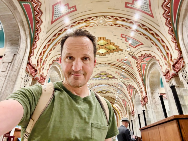 A smiling travel selfie of Jared Harding Wilson inside the historic Art Deco banking hall of the Guardian Building in Detroit.
