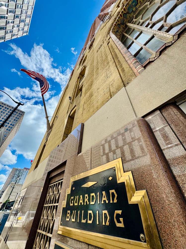 A wide angle view of the north side of the Guardian Building with the American flag under a blue sky, captured by Jared Harding Wilson.